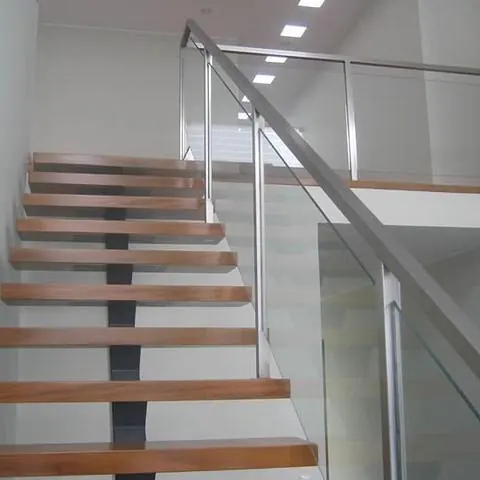 Escalera de peldaños de madera con barandilla de vidrio e inoxidable