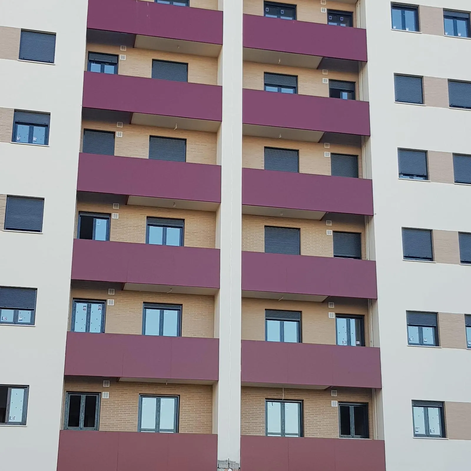 Edificio de viviendas con balcones revestidos de composite granate