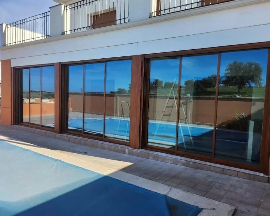 Cerramiento de aluminio imitación madera junto a la piscina