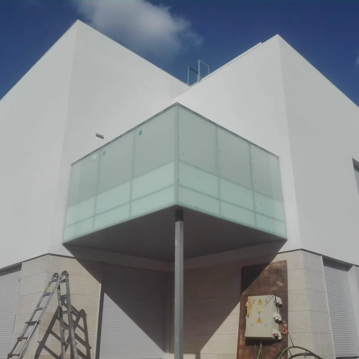 Balcón volado de vidrio en fachada blanca
